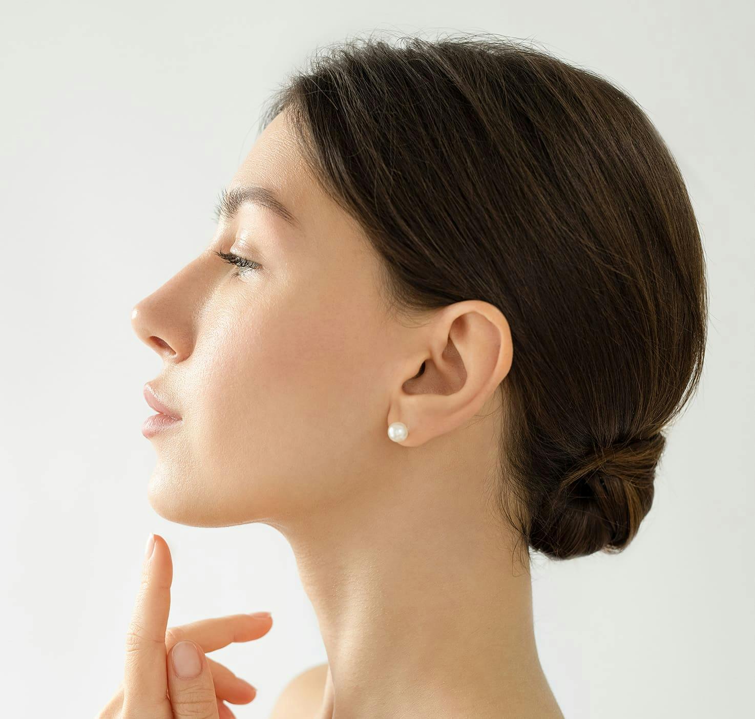 Side profile of woman pointing to chin