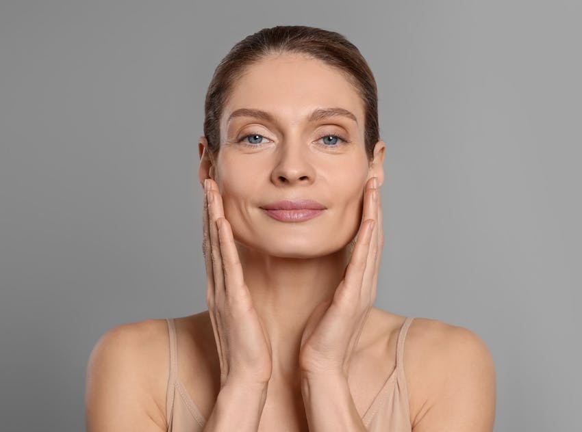 woman smiling while touch face with both hands