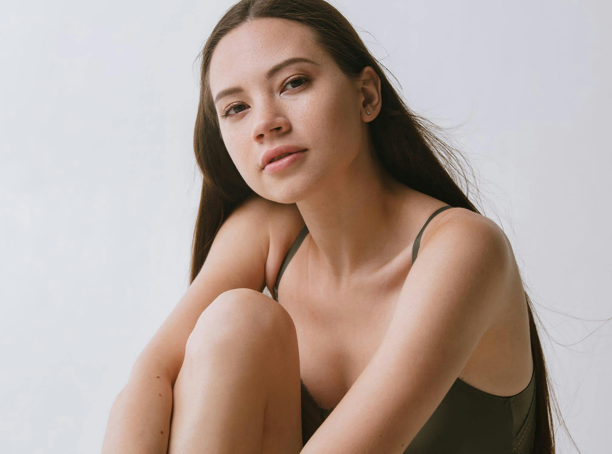 Woman smiling sitting on the floor with one knee up