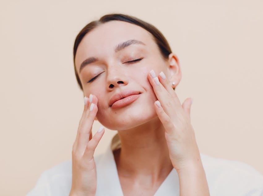 woman touching cheeks with eyes closed