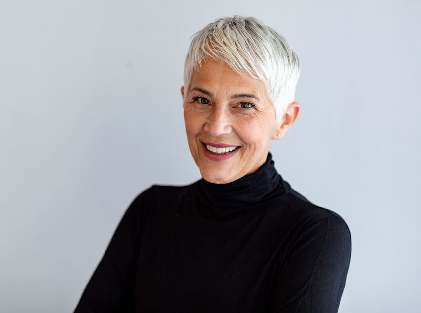 older woman smiling wearing a black turtle neck sweater