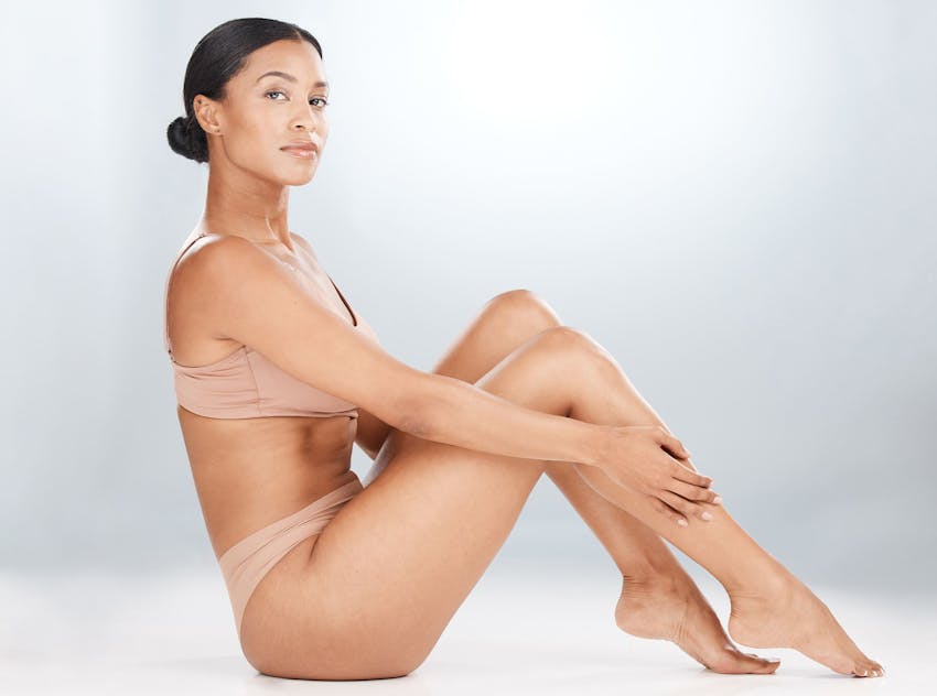 Woman sitting on the ground touching legs