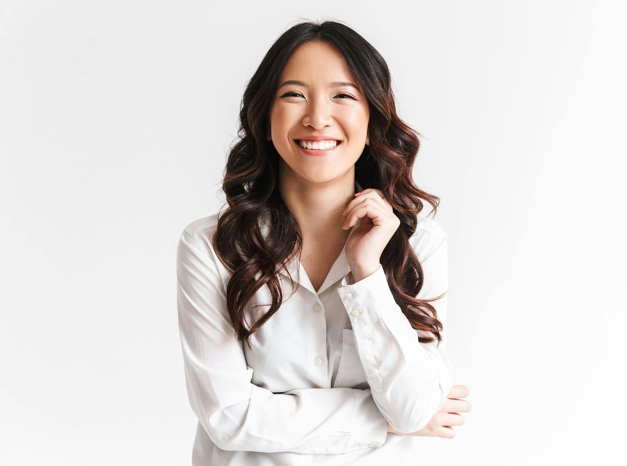 woman in white button down smiling with arms folded