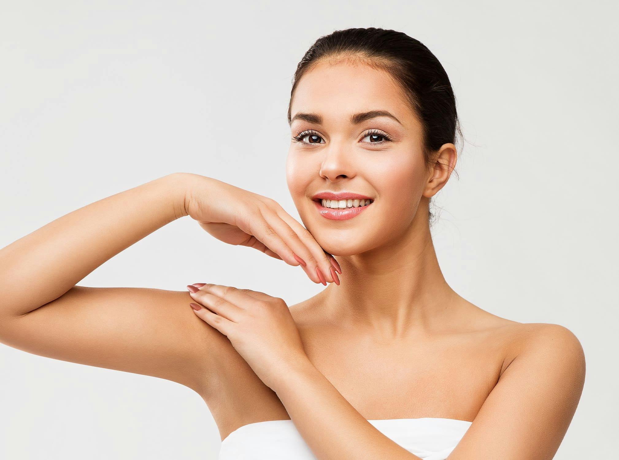 Woman smiling with one hand on shoulder and one hand on chin