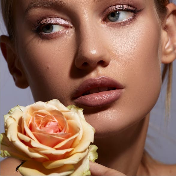 woman with a peach colored rose by her face