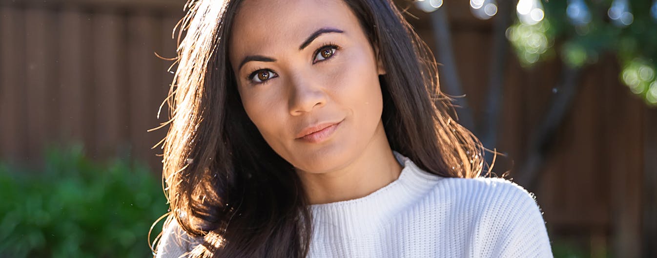 woman with long dark hair wearing a white top