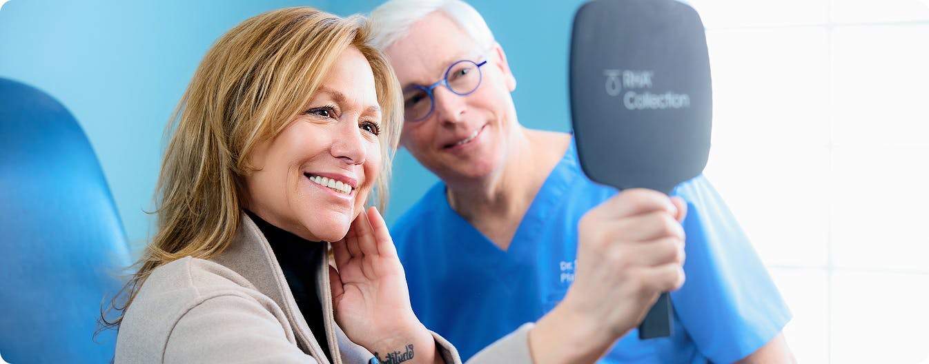 woman and doctor looking in a handheld mirror
