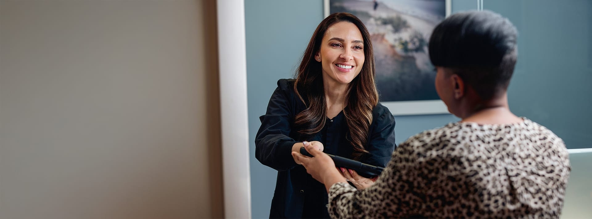 receptionist handing a woman a tablet