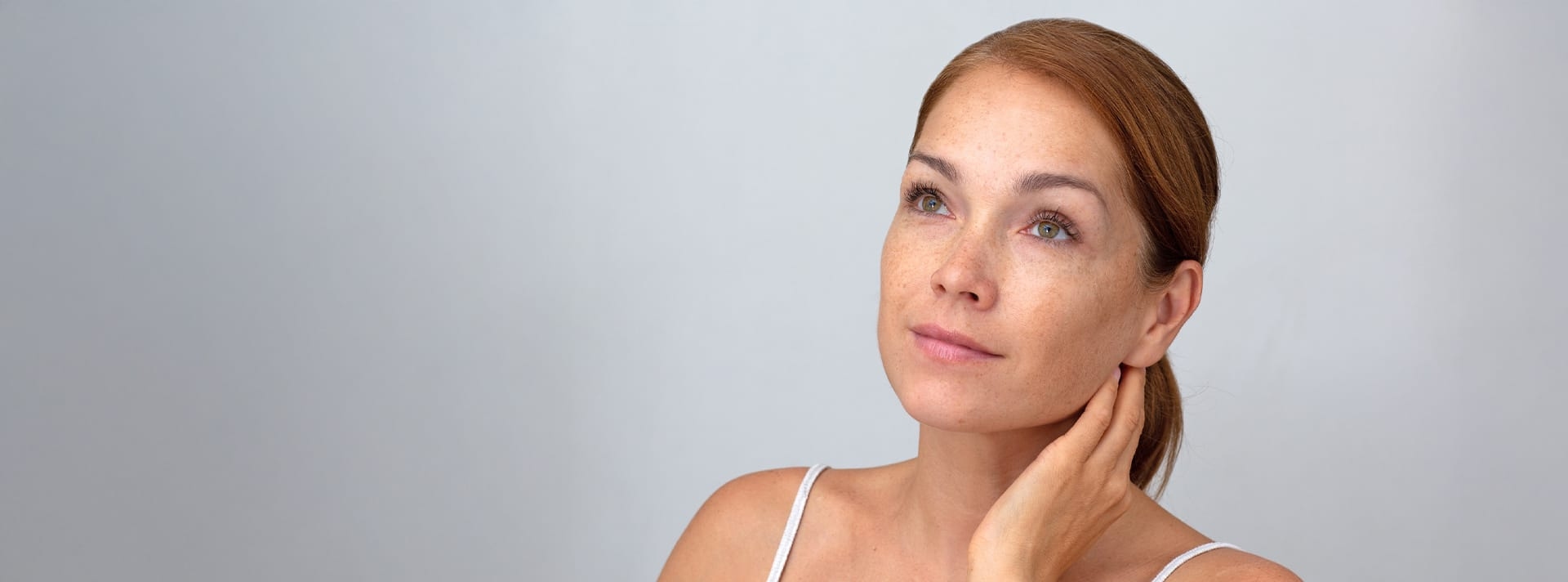 woman with her hair tied back and her hand on her neck