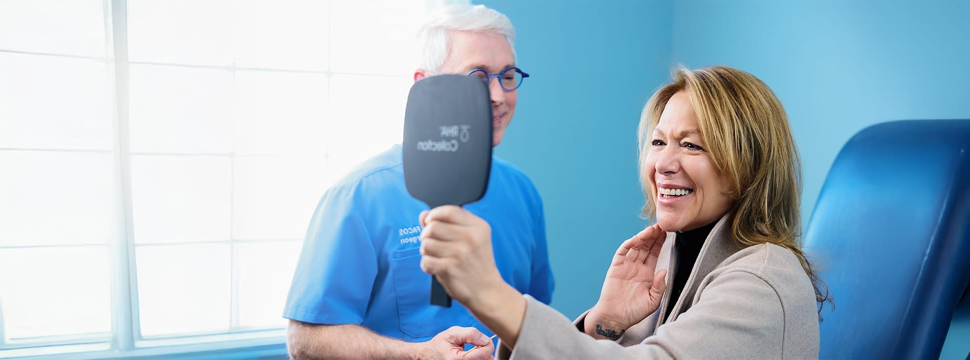 woman looking into handheld mirror with doctor next to her