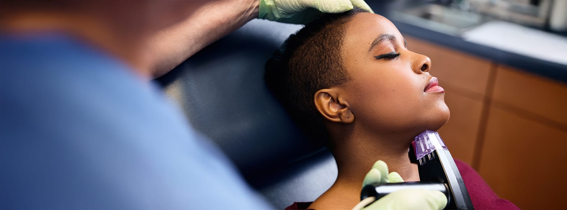 woman laying in examination chair with doctor looking at her skin