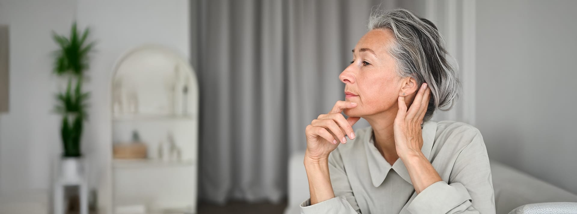 woman looking to the left with one hand on her neck and the other grabbing her chin