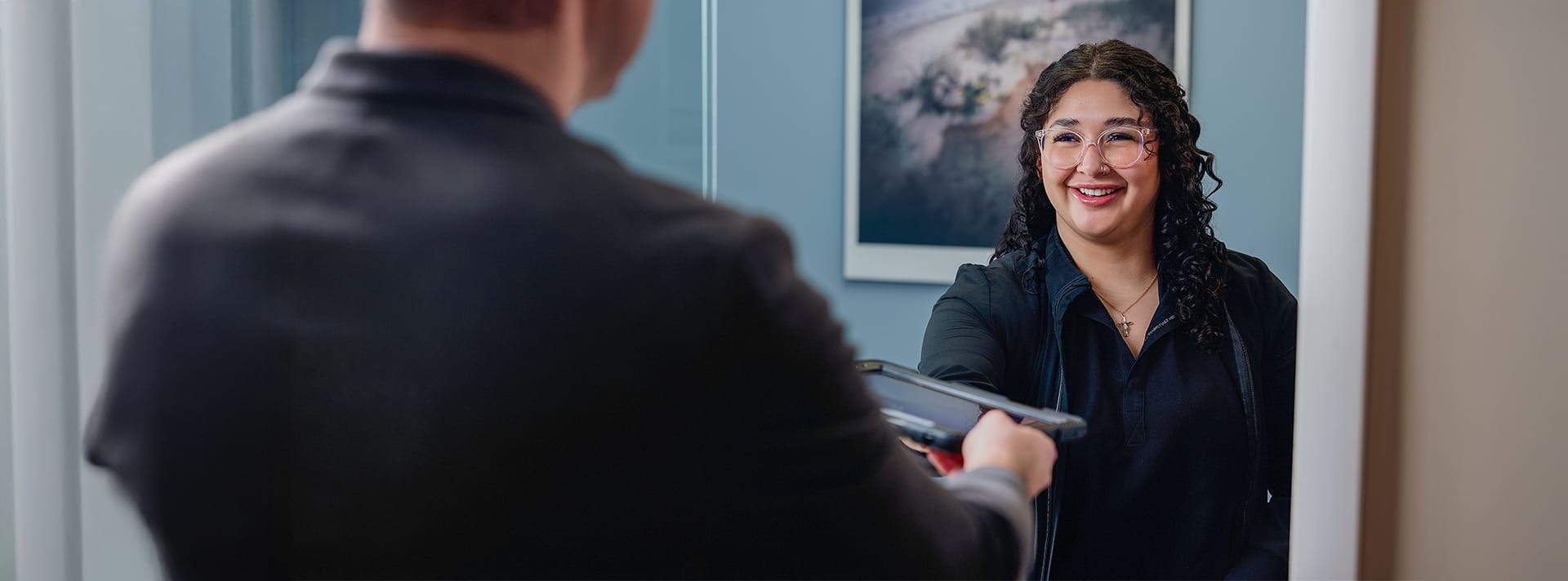 man handing a woman a tablet