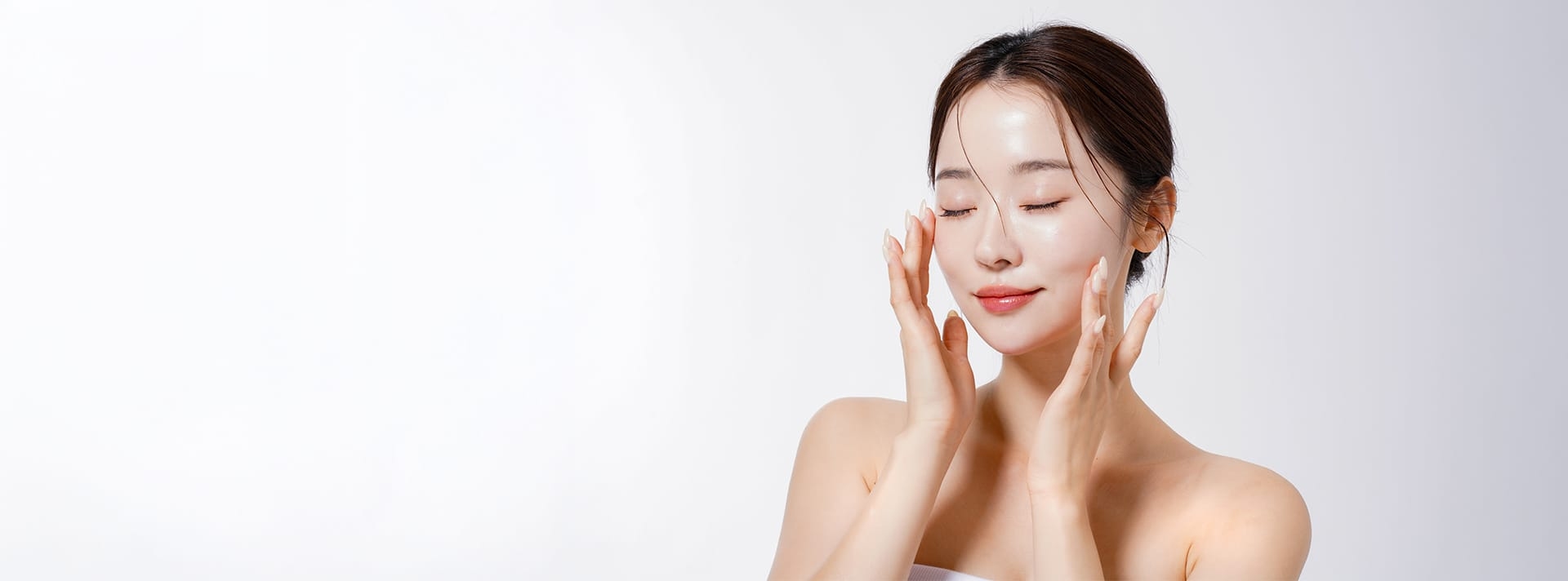 Woman with wet skin smiling with hands on face