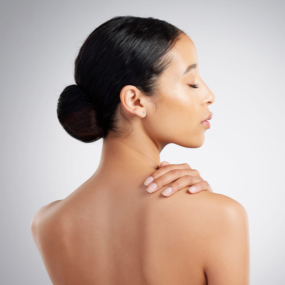 woman facing away with her head facing the right and hand on her shoulder