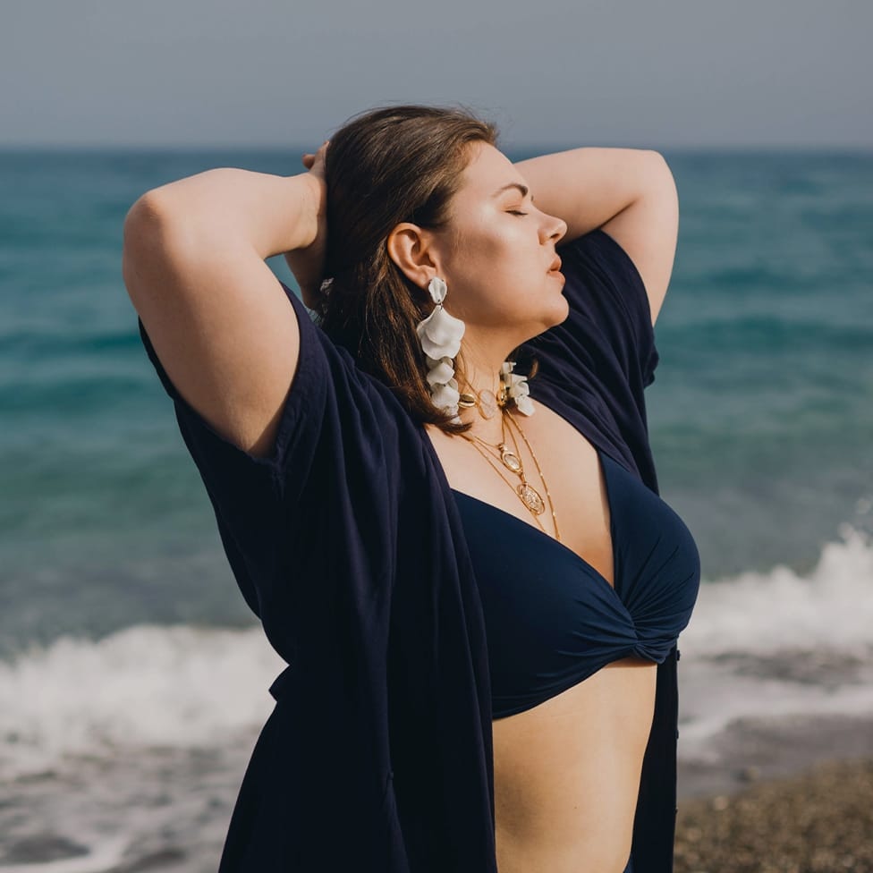 woman with her hand behind her head on the beach