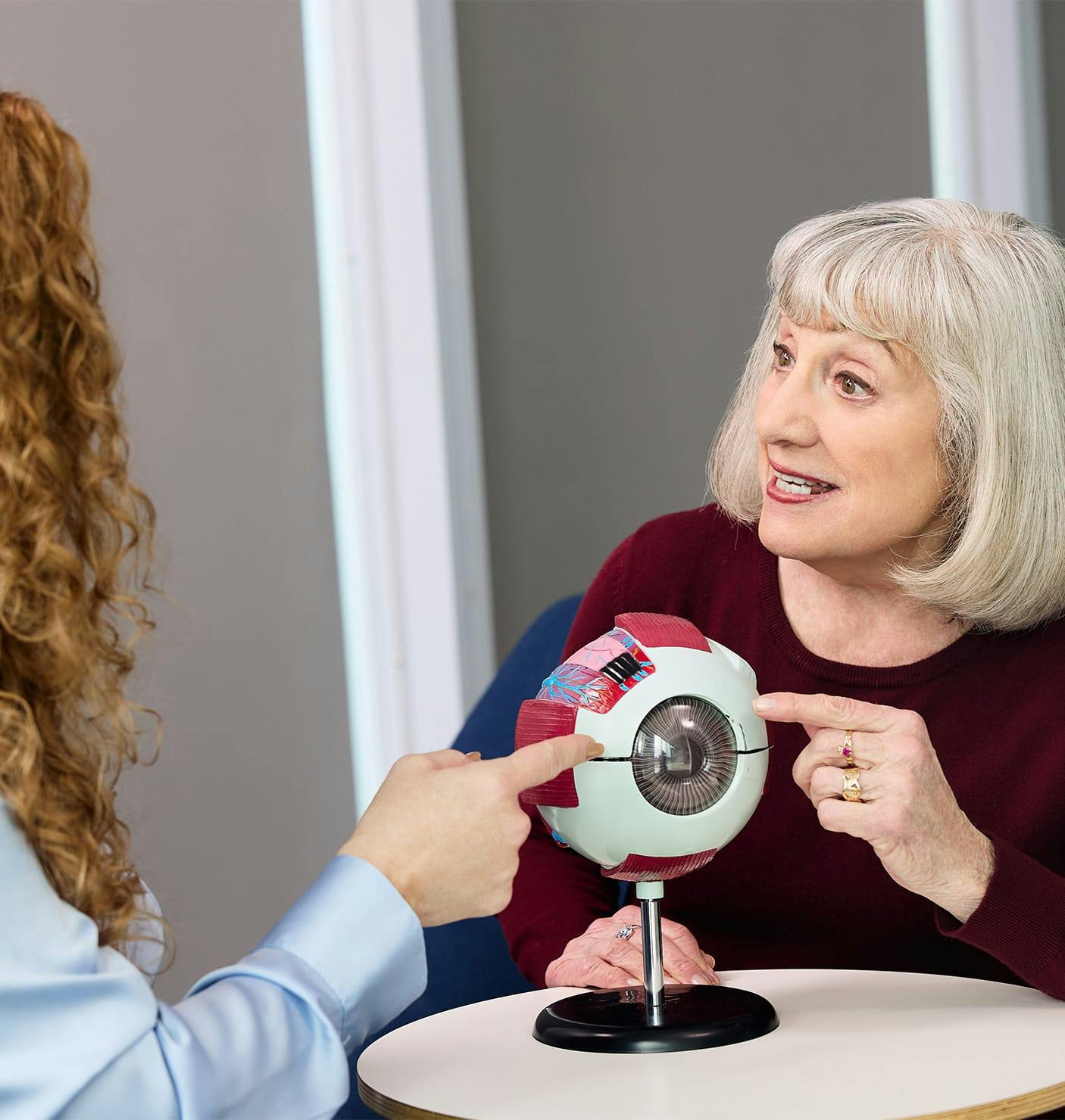 doctor showing a patient a 3D eye diagram