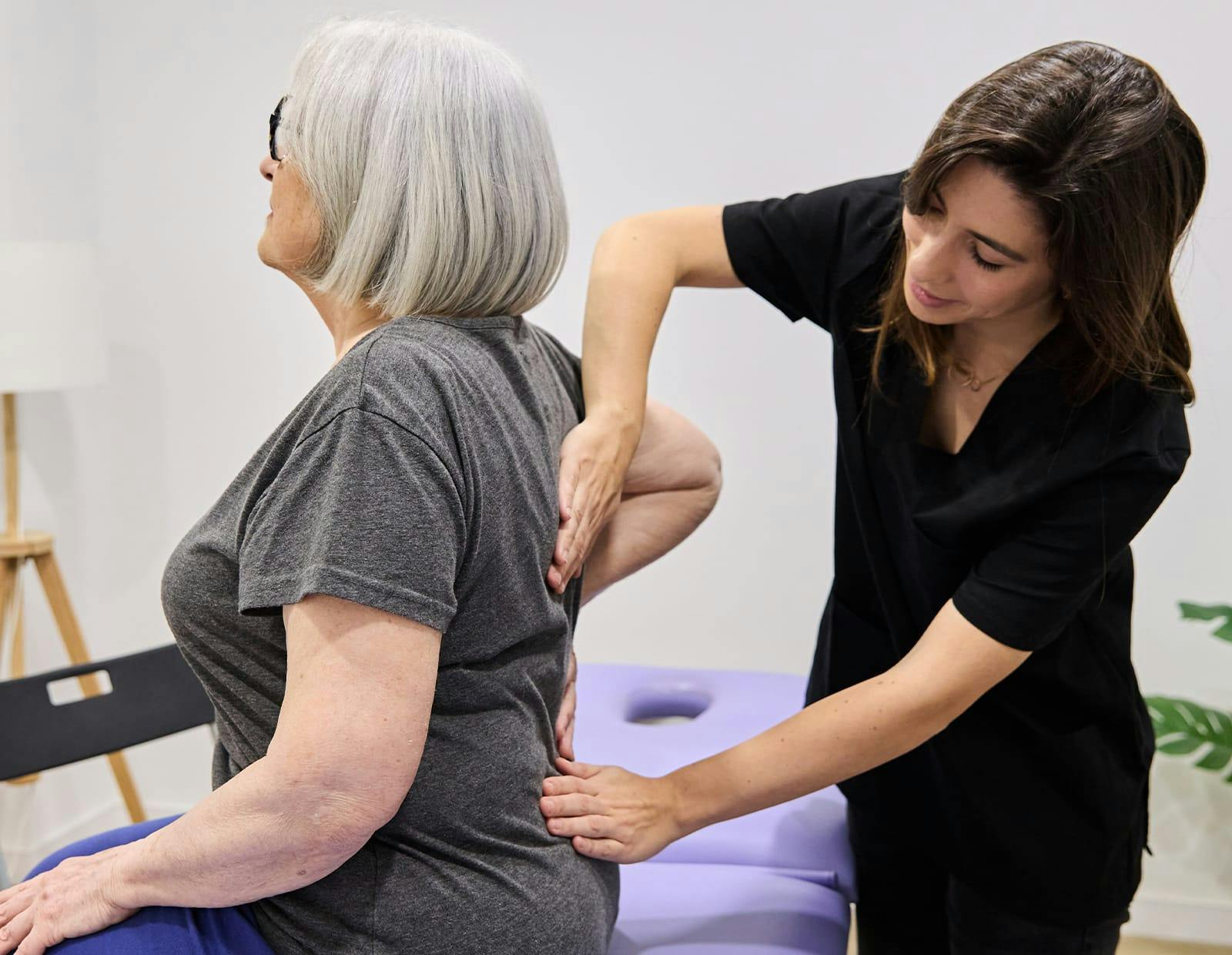 Physical therapist applying pressure to patient’s lower back during evaluation