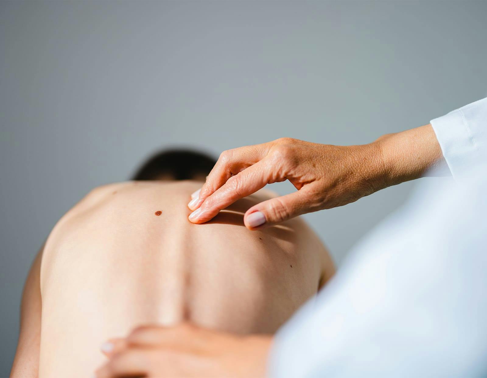 Medical professional examining patient’s upper spine with hands