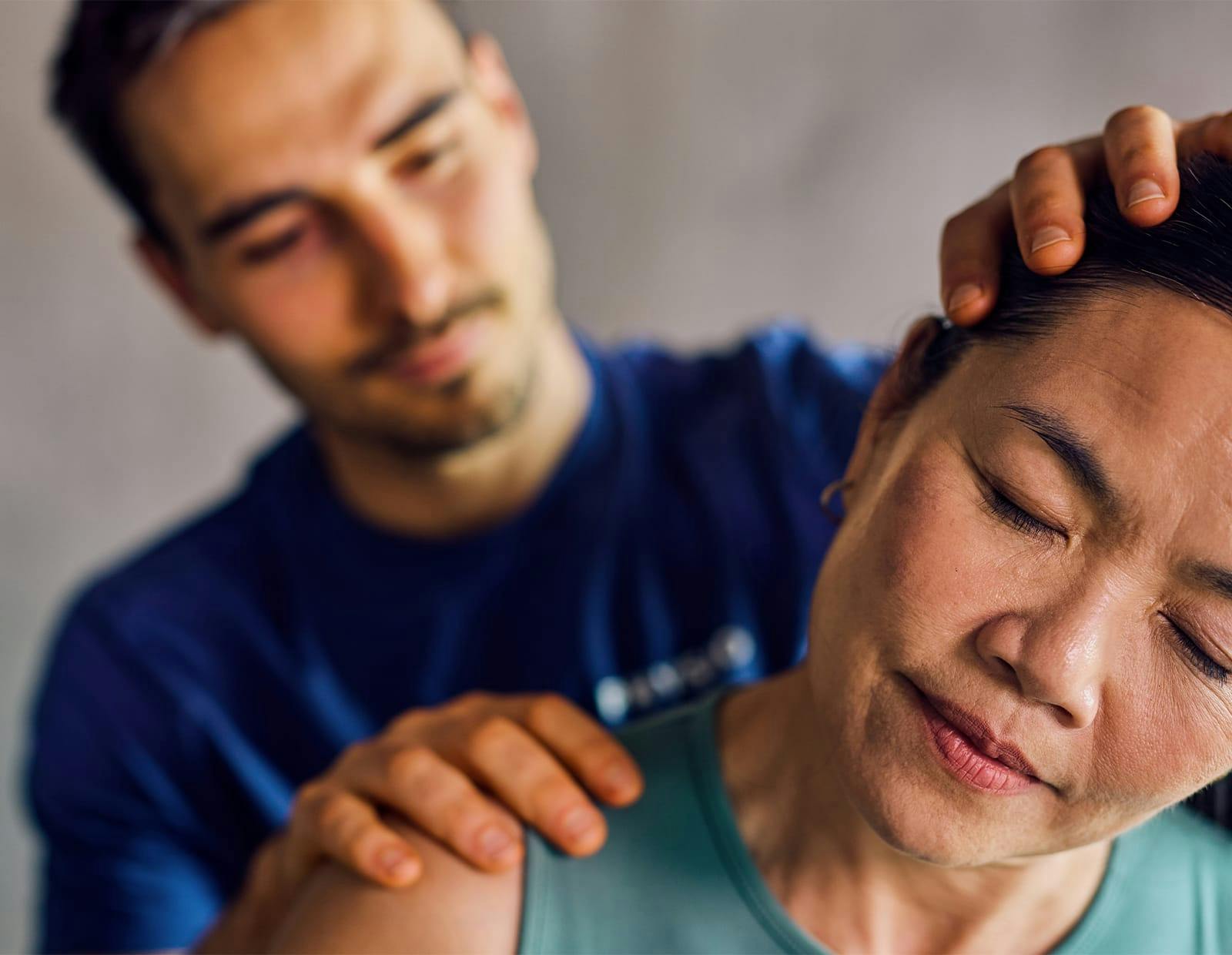 Physical therapist assisting woman with neck stretch