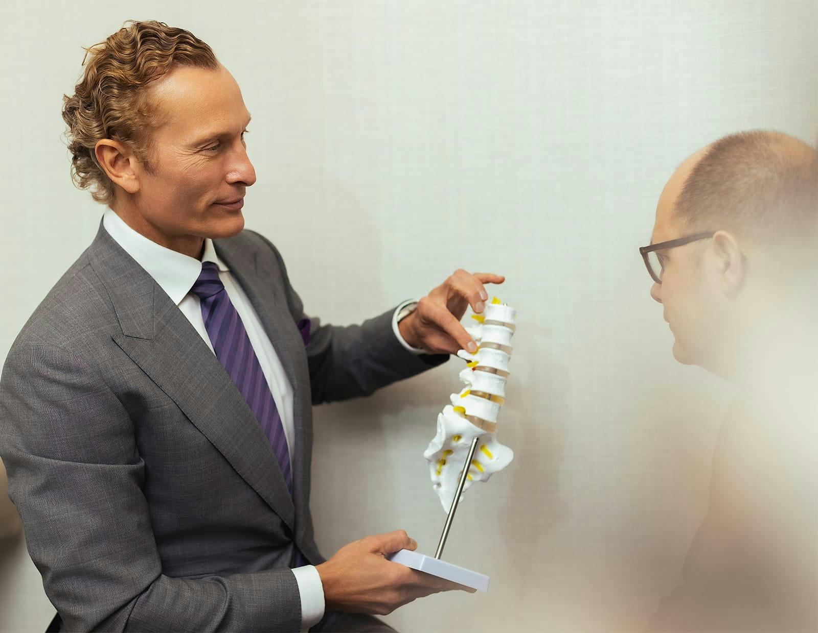 Doctor Gerling holding a spine model, talking to a patient