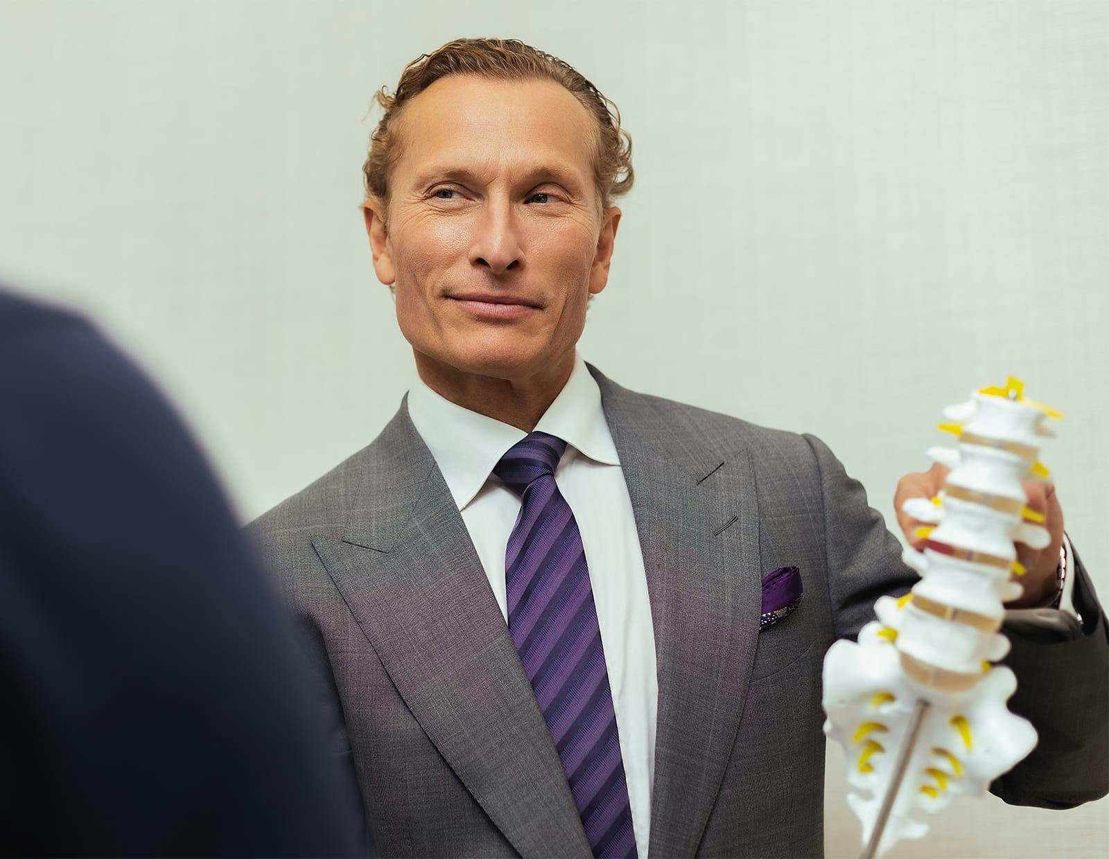 Dr. Michael Gerling, spine surgeon, holding a spine model and discussing treatment options with a patient
