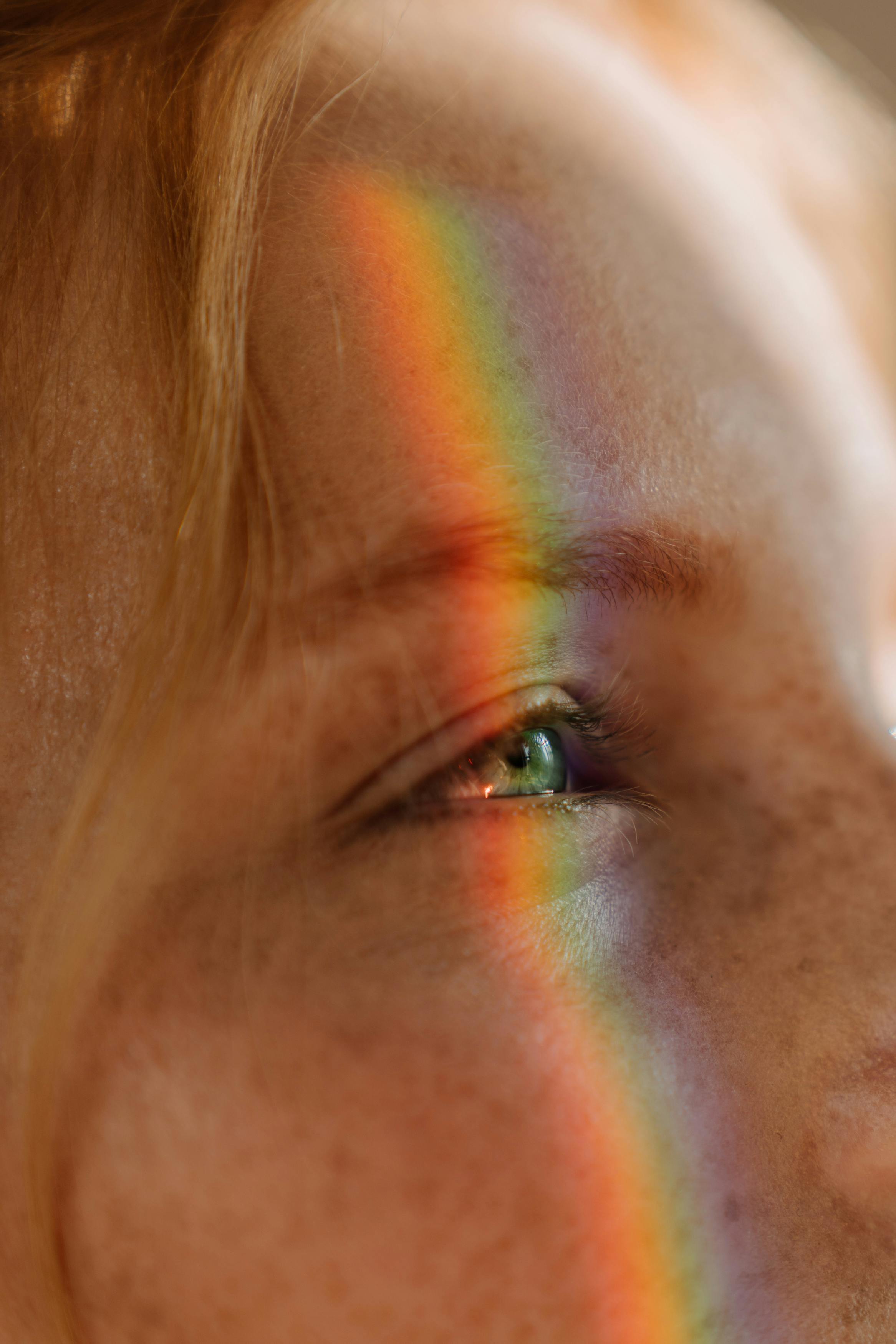 Woman with rainbow light over eye