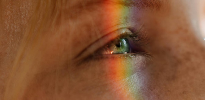 Woman with rainbow light over eye