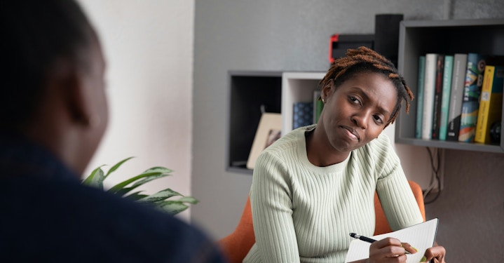 Therapist writing down notes and looking intently at other person