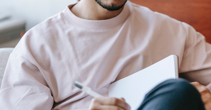 person journaling for mental health, holding notebook on their lap while writing