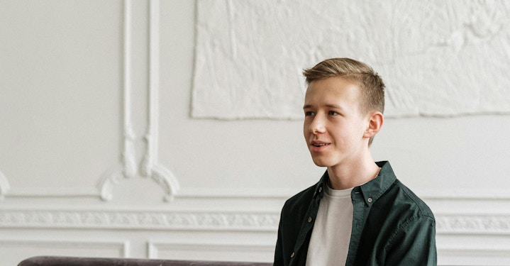 A young person sitting in a therapist’s office, looking uncertain or hesitant during a therapy session.