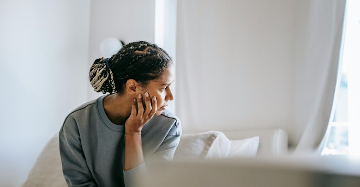 A person rests their chin on their hand, appearing deep in thought as they prepare for a therapy session and consider what to talk about.