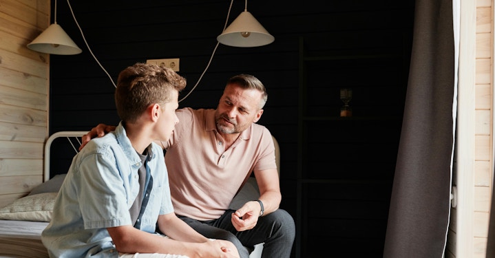 Parent and teen sitting on bed, presumably discussing AI therapy