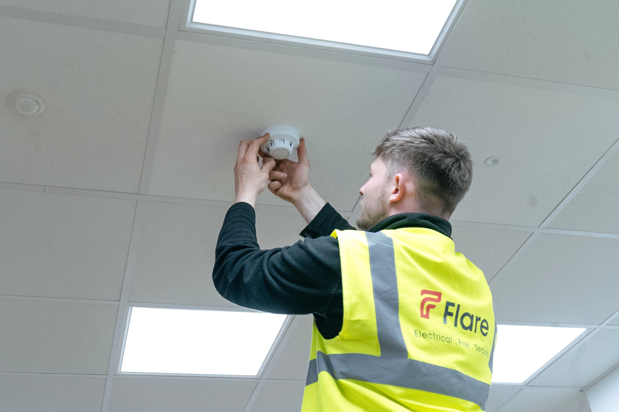 Flare EFS engineer checking a smoke detector during a fire alarm service
