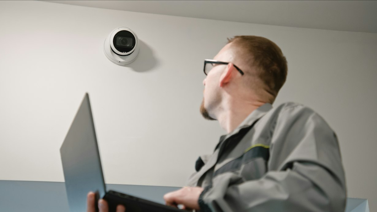A technician servicing a CCTV camera using a laptop