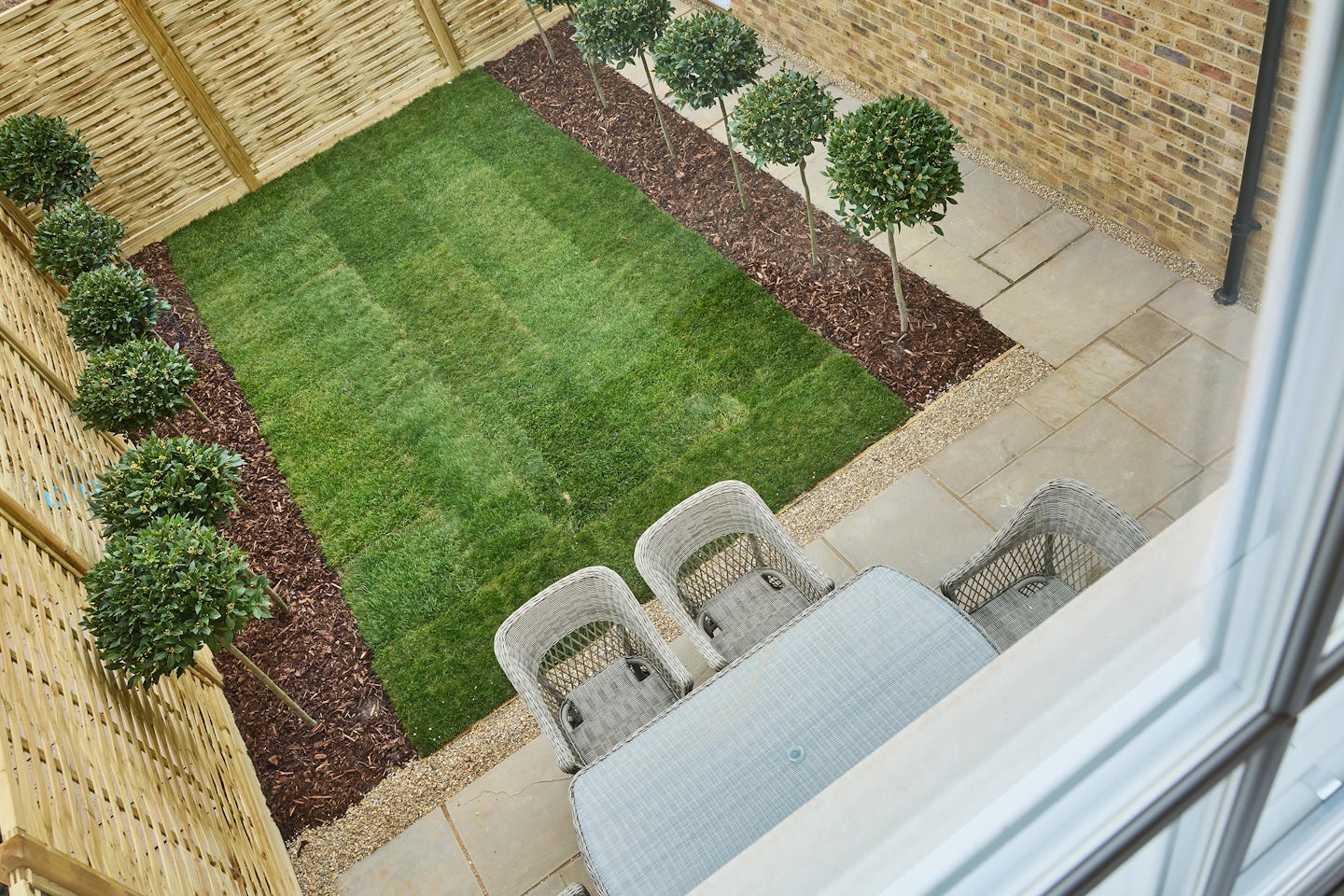Turfed garden with wooden fence, brick garage wall, table and chairs viewed from an upstairs window at the Burlington, Welborne.