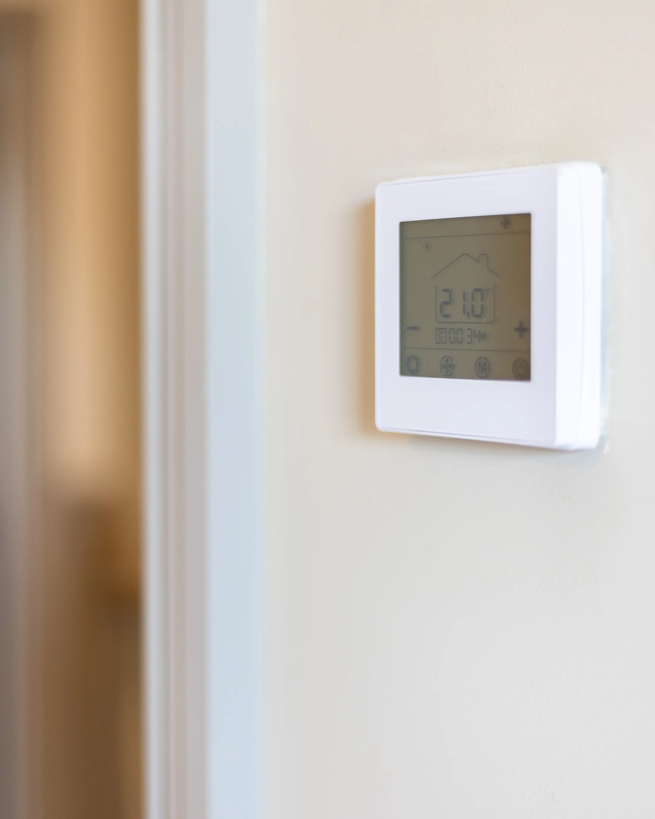 A sleek, modern thermostat mounted on a wall, featuring a digital display. The screen displays the current temperature and various settings, emphasizing its role in regulating indoor climate for comfort and energy efficiency.