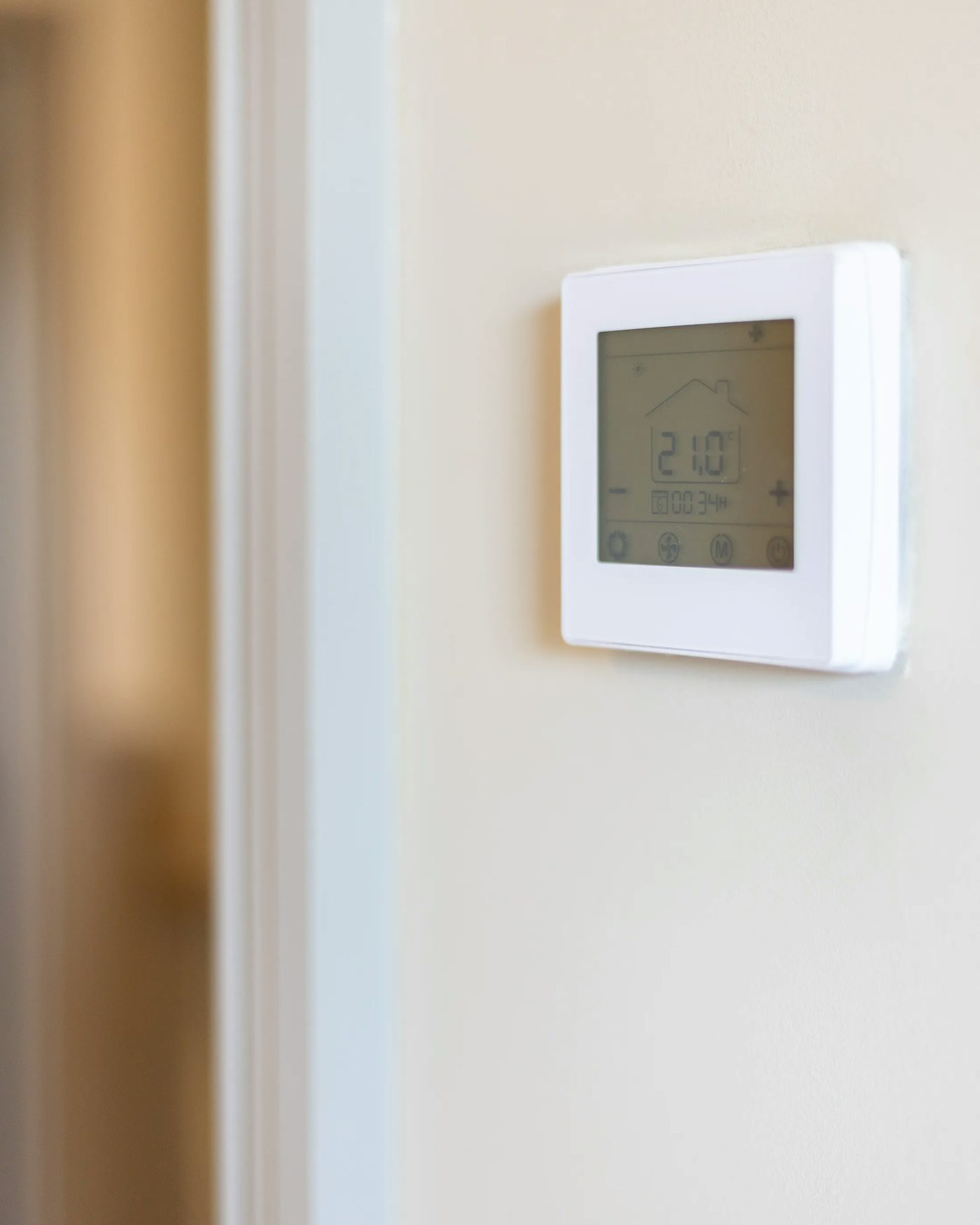 A sleek, modern thermostat mounted on a wall, featuring a digital display. The screen displays the current temperature and various settings, emphasizing its role in regulating indoor climate for comfort and energy efficiency.