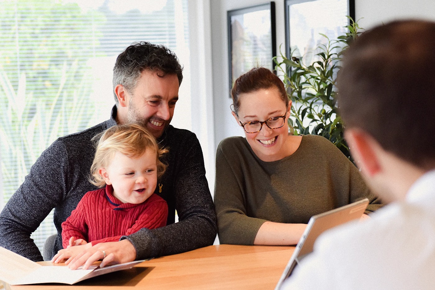 Happy family looking at a document or tablet together at a light wooden table.