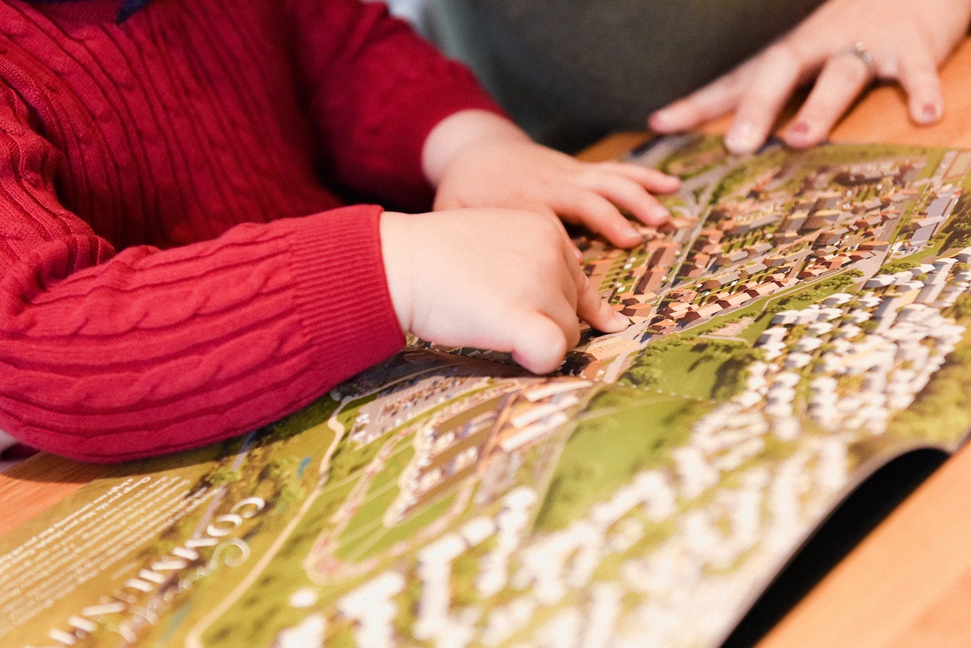 Child in red sweater examining a detailed map of a housing development.