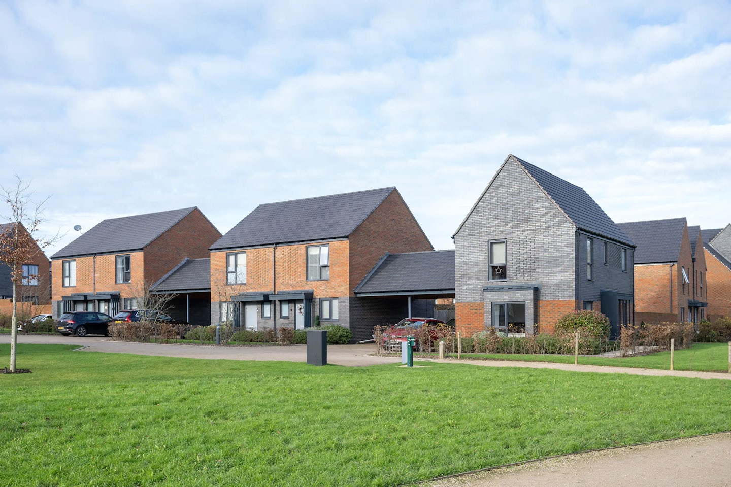 A row of semi detached starter homes for first time buyers. A large green space is in front of the houses.