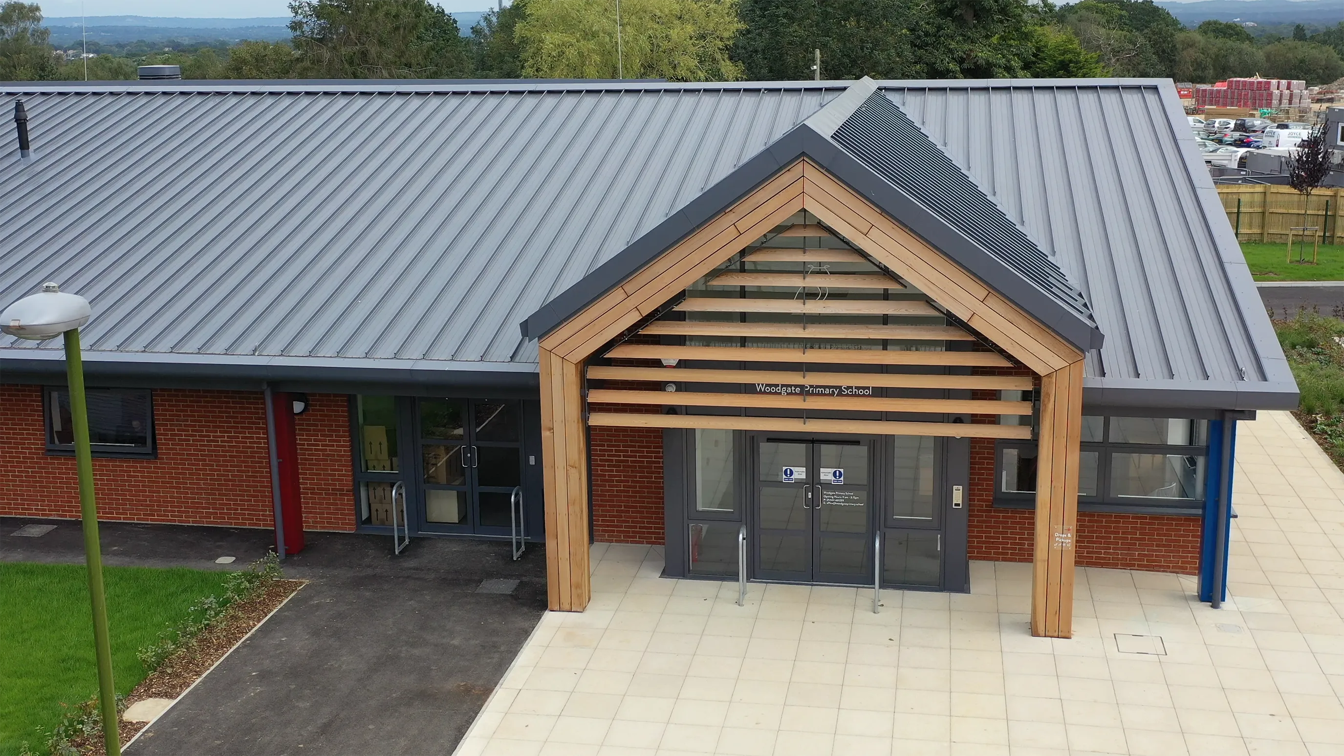 An aerial shot of the entrance to the Woodgate Primary School. The roof is corrugated, and the entrance has a wooden frame in a nordic style.