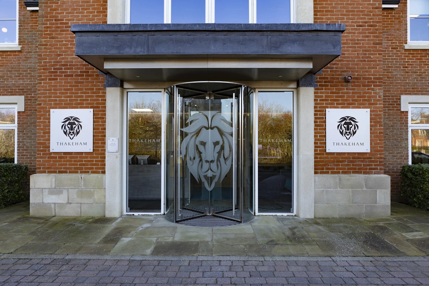 The front entrance of the thakeham head office building. A revolving door with the image of the company lion is visible.
