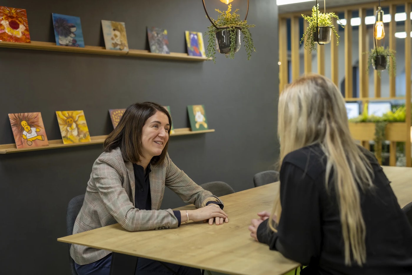 Two office workers sit opposite each other in a kitchen space.