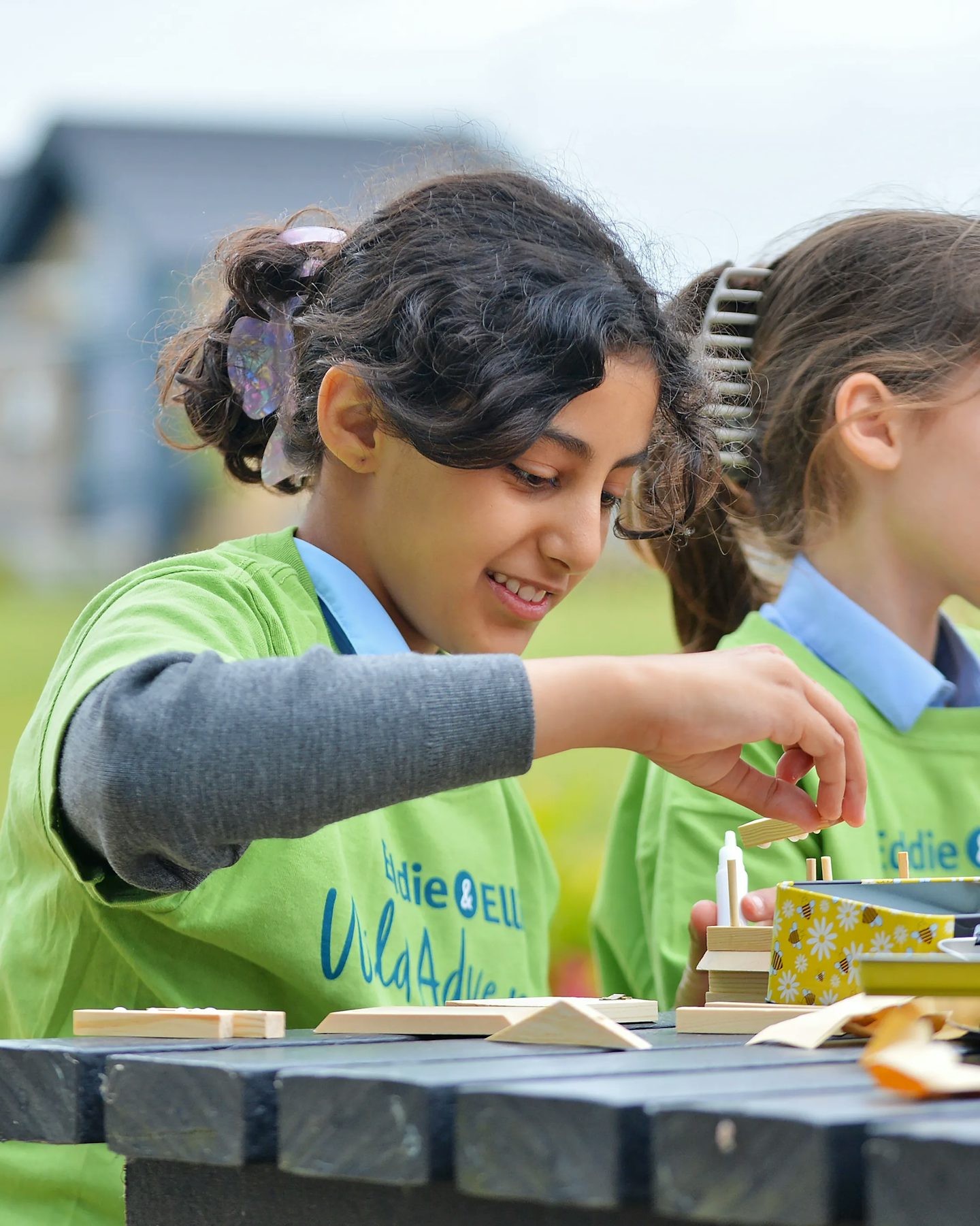 a child takes part in the eddie and ellie class to create bee hotels. Out of focus behind them is a nordic style villa at Woodgate.