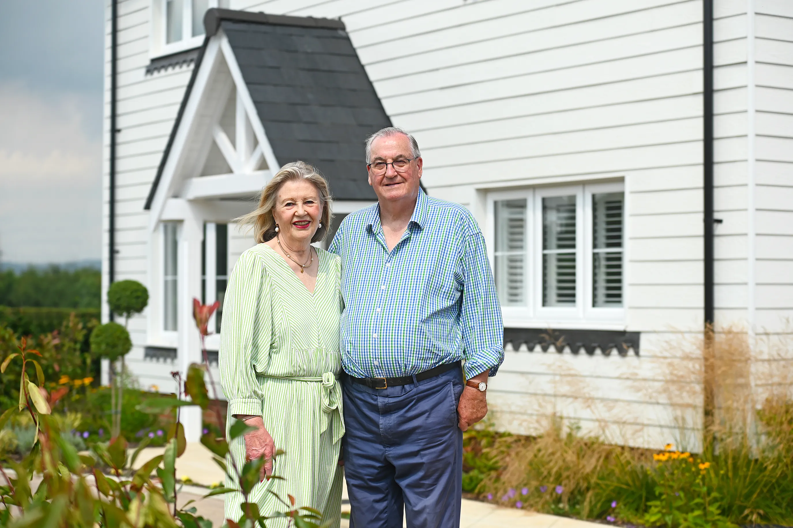 Richard and Sue stand outside their new home in Newick. The house is clad in a light grey cladding.