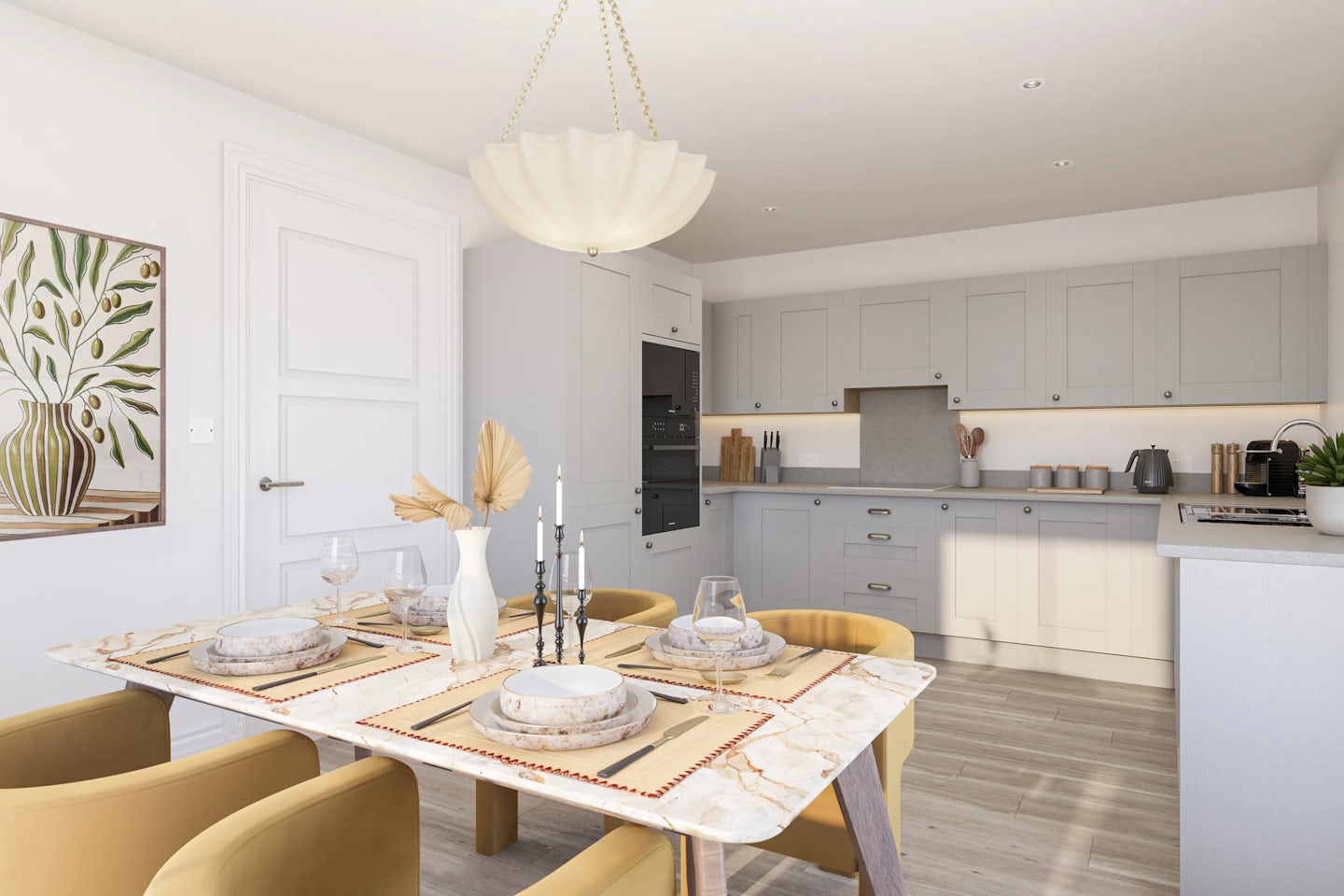 A modern kitchen and dining space featuring a light wood floor, pale grey cabinetry, and integrated appliances. A rectangular dining table is neatly set for four, with plates, bowls, and glasses, accented by a central white vase of dried foliage and slender candle holders. Mustard yellow upholstered chairs surround the table beneath an elegant chandelier. The adjoining kitchen includes a toaster, kettle, and coffee machine arranged on the countertop. A framed artwork depicting a leafy vase hangs near the doorway, adding a serene decorative touch.