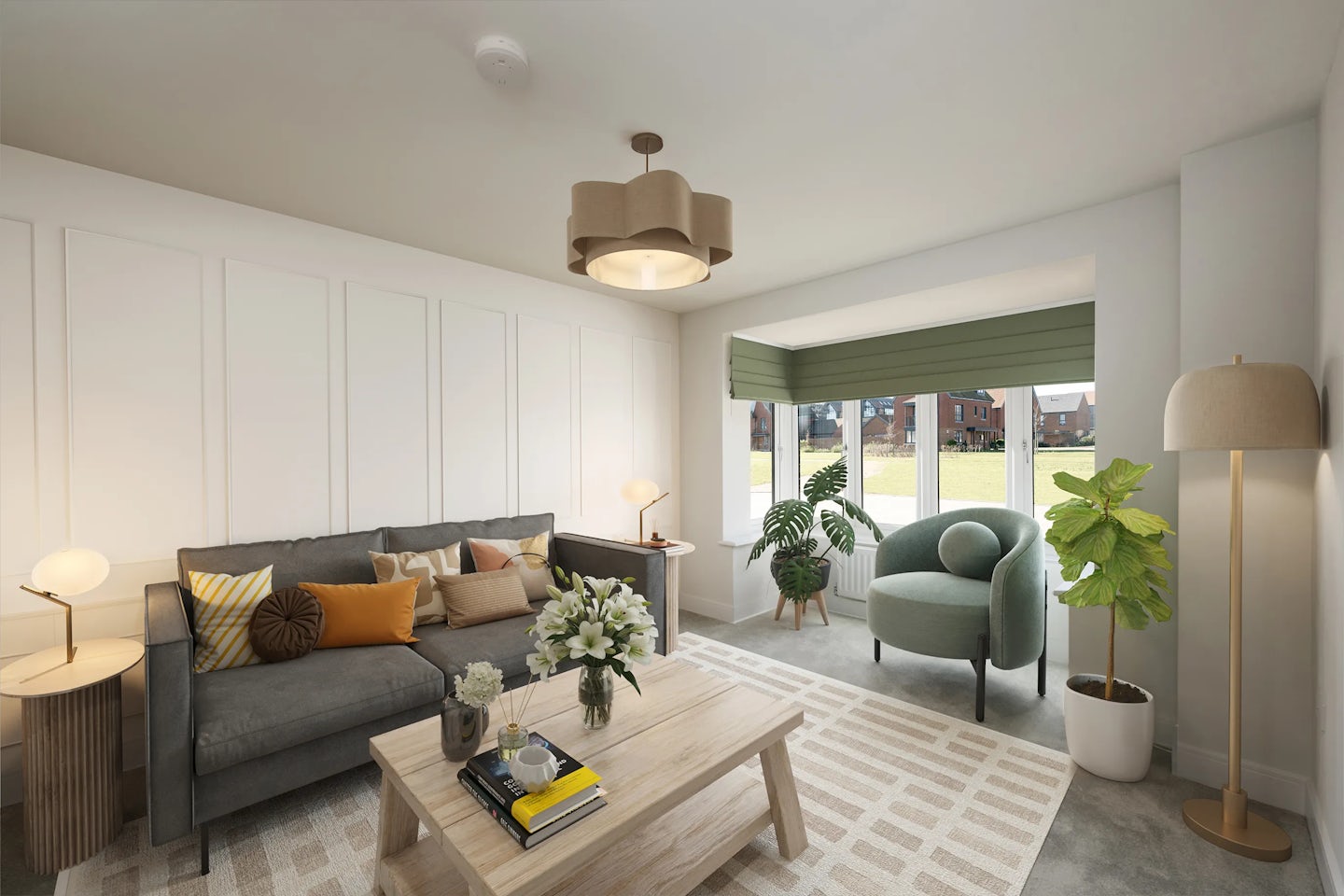 Modern living room with a grey sofa adorned with colourful cushions, a wooden coffee table holding a floral vase, mug, and books, and a green armchair beside a large window with green blinds. A round side table with a lamp sits to the left of the sofa, while a floor lamp and potted plant frame the seating area. The room features a light geometric-patterned rug, white panelled walls, and a ceiling light fixture. Outside the window, a grassy view with distant houses enhances the serene setting.