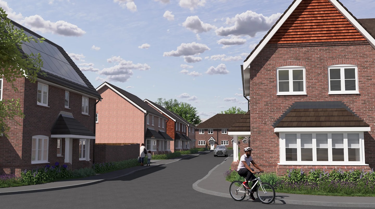 CGI of a tree-lined residential street with brick houses featuring pitched roofs, white window frames, and visible solar panels. A cyclist rides past in the foreground, while a pedestrian walks along the pavement. A parked car and partly cloudy sky add to the serene, eco-aware suburban scene.