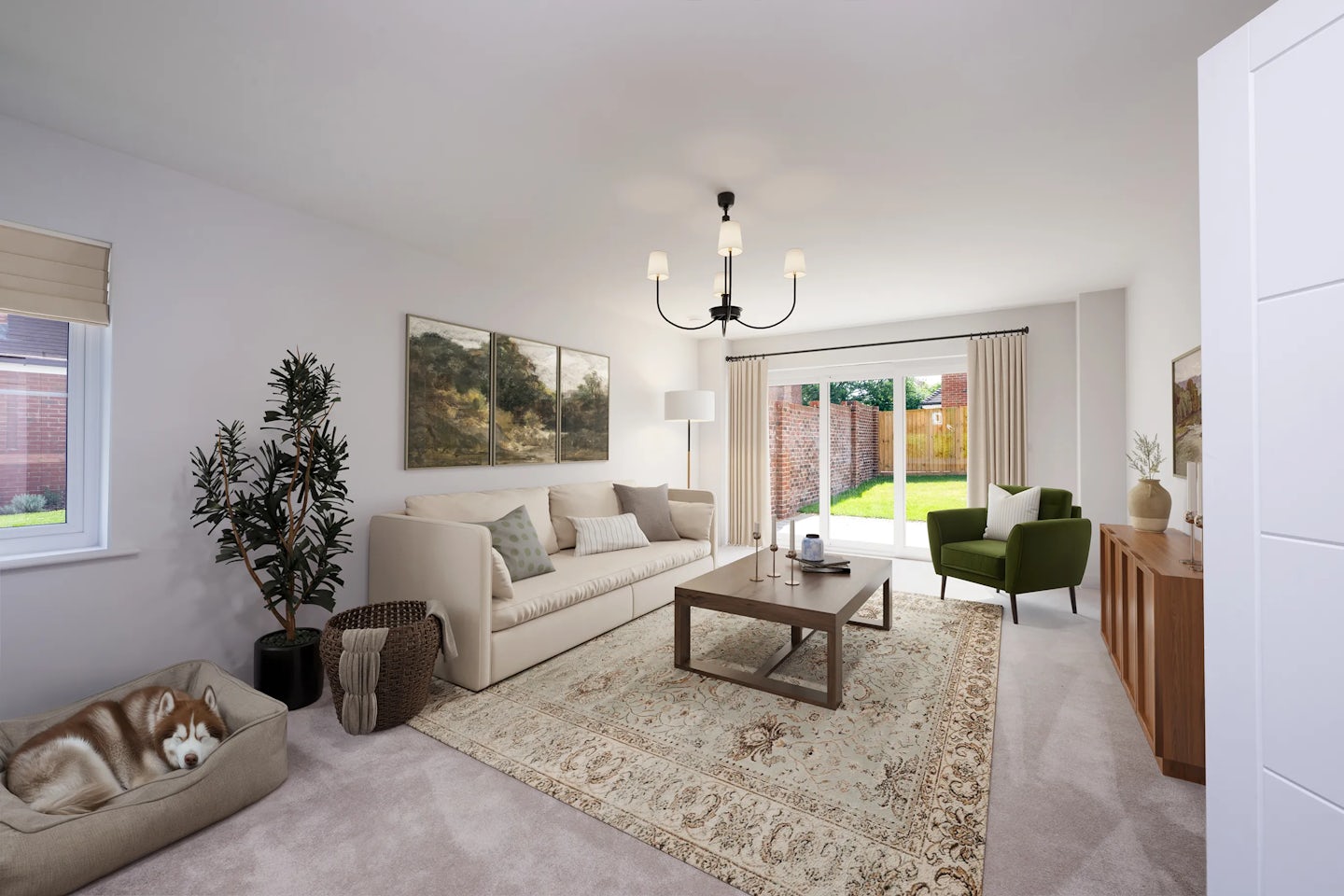 Well-furnished living room with a beige sofa, two green armchairs, wooden coffee table, and patterned rug. A dog sleeps in a bed on the left, with a large window opening to a garden, paintings on the walls, an indoor plant by the sofa, and a chandelier overhead.
